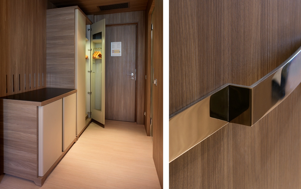 Un placard de chambre d'hôtel moderne conçu pour un aménagement de luxe est présenté ouvert, révélant des cintres à l'intérieur de ses panneaux en bois et de sa porte en verre. À côté, un gros plan de la poignée en métal élégante du placard, soulignant l'agencement contemporain et les lignes épurées.