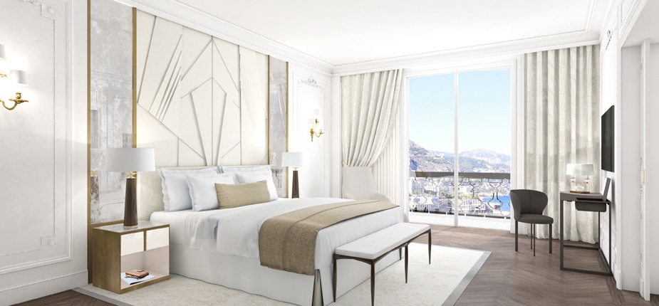 A modern, luxurious bedroom exuding a boutique feel, featuring a large bed with white linens and beige accents flanked by nightstands with lamps. The room boasts chic decor with geometric wall art, a bench at the foot of the bed, a desk and chair, and large windows offering stunning mountain views.