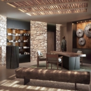 L'intérieur moderne du Dolce by Wyndham Versailles présente des murs en pierre, des poutres en bois, un long banc rustique, des étagères avec des bouteilles, une grande table avec des chaises et des œuvres d'art murales composées de morceaux de pierre ronds du Domaine du Montcel. Un éclairage doux crée une ambiance chaleureuse.