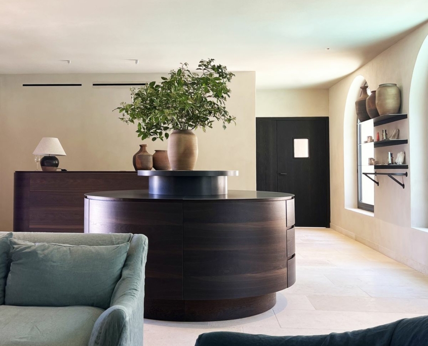 Comptoir d'accueil rond en bois foncé et niches cintrées – Île de Bendor, agencement GH & Partners