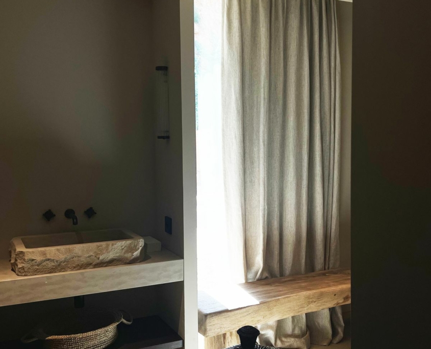 Salle de bain avec vasque en pierre taillée et banc en bois massif – Île de Bendor, GH & Partners